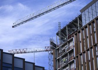 Rakennustyömaa, jossa kaksi torninosturia ja keskeneräinen monikerroksinen rakennus.
